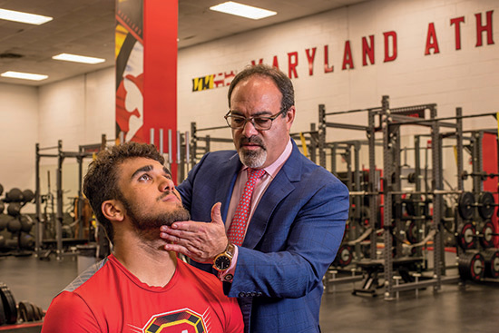 Orthopedic doctor Andrew Pollak examines an athlete's neck for a sports injury